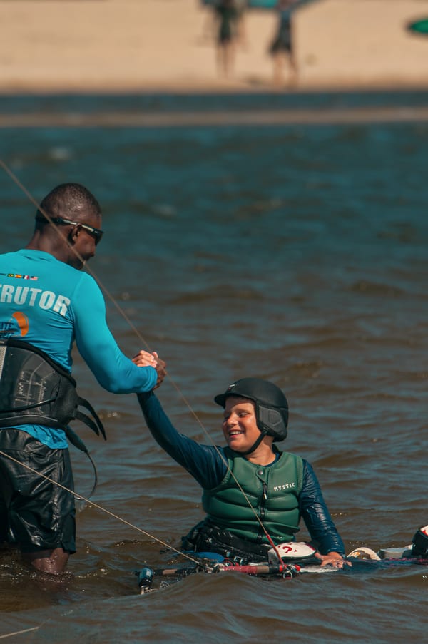 Wendell reaching down to hold a smiling young student's hand in the lagoon